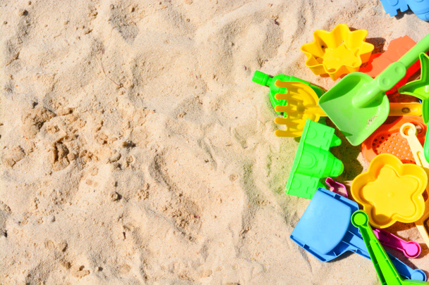 Много красочных пляжных игрушек, лежащих на песке
 - Фото, изображение