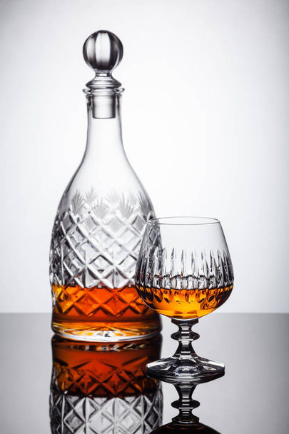 Kristallen karaf en glazen met rum, Karaf met whisky op een glazen tafel, witte achtergrond - Foto, afbeelding