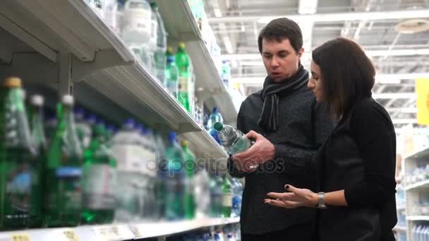 junges Paar mit Begeisterung wählt Mineralwasser für den Hausgebrauch. - Filmmaterial, Video