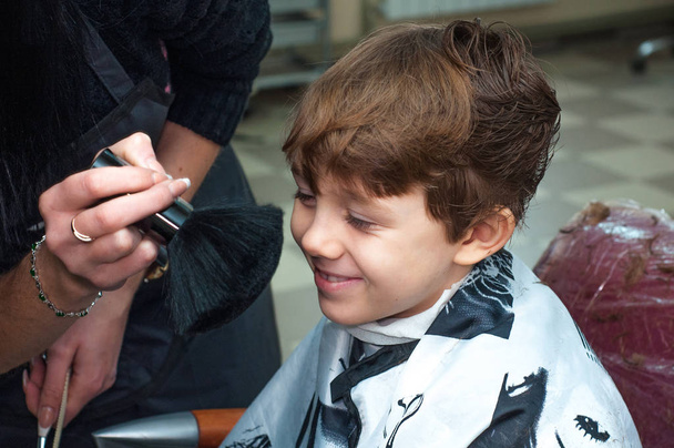 Hairdresser brushing the boy's face thick brush after hair cutting - Fotoğraf, Görsel