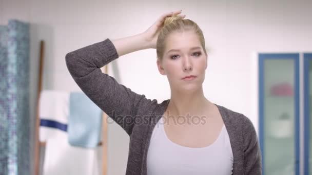 Attractive woman opens her hair with a critical look in the mirror - Filmagem, Vídeo