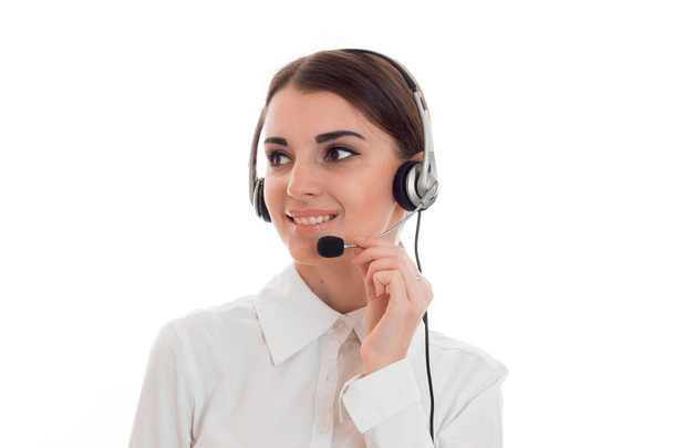 junge schöne brünette Geschäftsfrau mit Kopfhörer und Mikrofon lächelnd und wegschauend isoliert auf weißem Hintergrund - Foto, Bild