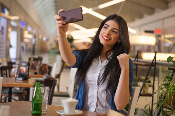 Νεαρή γυναίκα να κάνει μια selfie σε ένα καφέ - Φωτογραφία, εικόνα