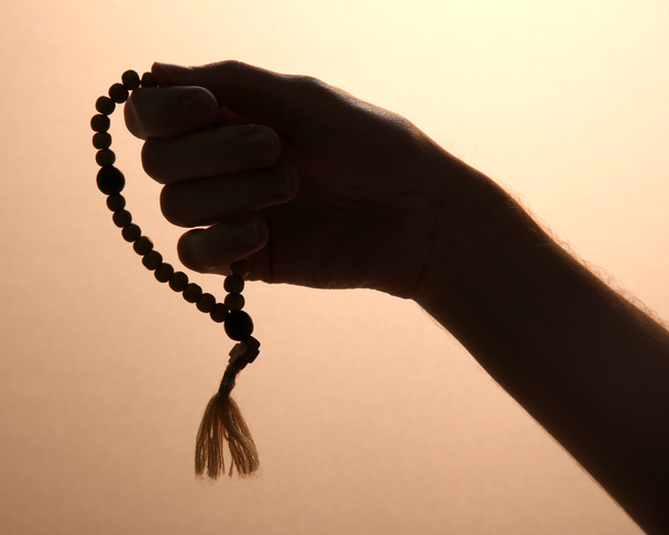 male hand with rosary, on brown background - Foto, Bild