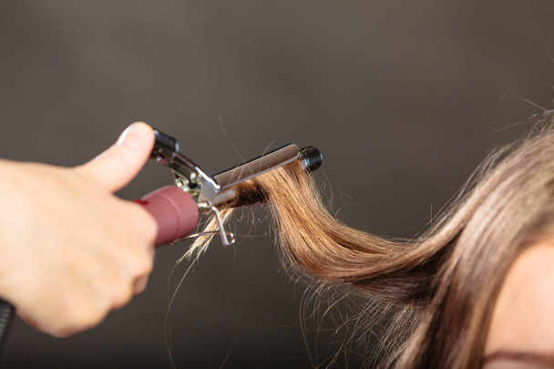Στυλίστρια μπούκλες μαλλιά για τη νεαρή γυναίκα. - Φωτογραφία, εικόνα