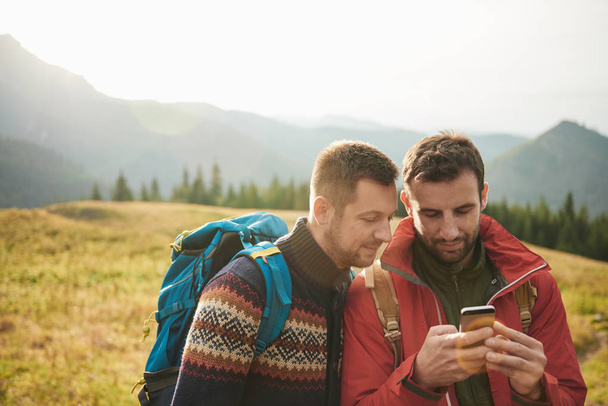 Men in hiking gear using cellphone  - Foto, Imagem