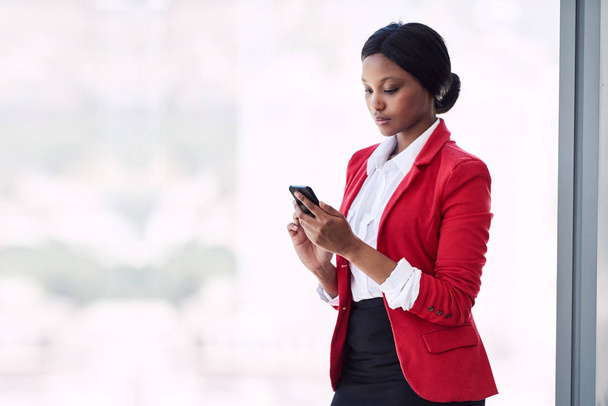 Young formally dressed african american woman busy using her phone - Foto, afbeelding