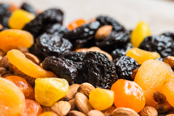 prunes, dried apricots, dried mandarins and almonds on a light wooden background - Photo, Image