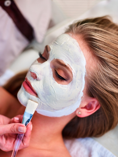 Facial treatment of woman. Clay face mask and beautician hands. - Photo, Image