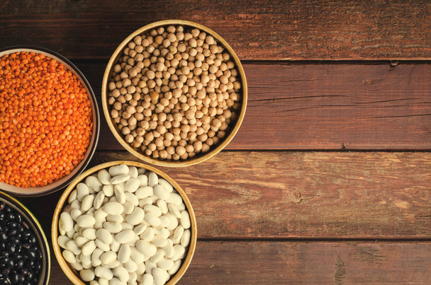Assorted beans in bowls with red lentil, chick-pea and kidney bean on wooden background. - Foto, Imagem