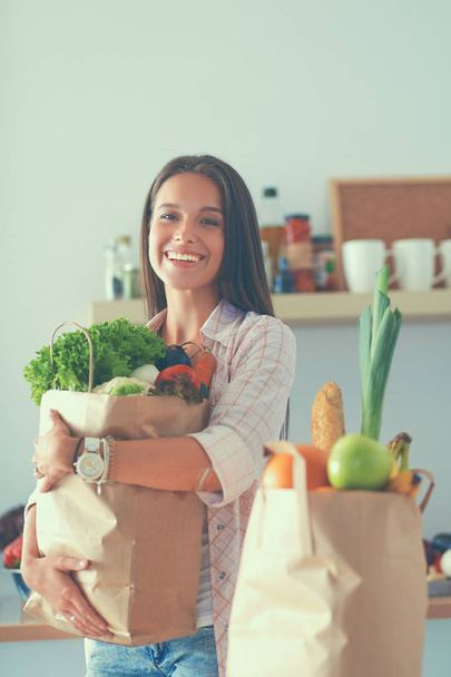 Νεαρή γυναίκα κρατώντας τσάντα ψώνια με λαχανικά - Φωτογραφία, εικόνα