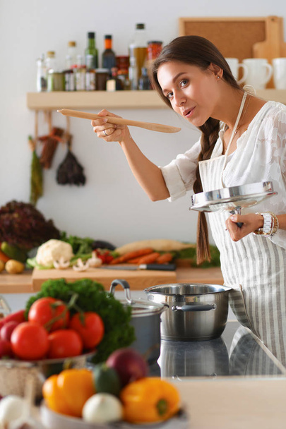 Cooking woman in kitchen with wooden spoon - Foto, Bild