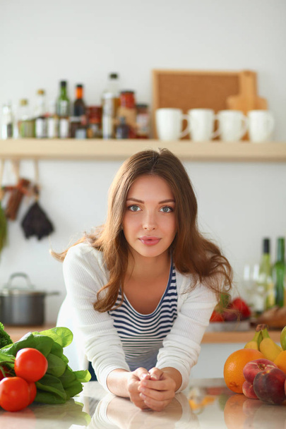 Молодая женщина, стоящая возле стола на кухне - Фото, изображение