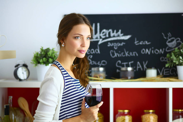 Pretty woman drinking some wine at home in kitchen - Photo, image