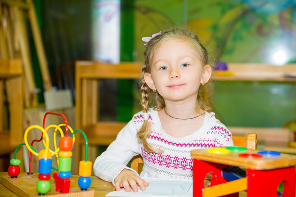Adorable child girl playing with educational toys in nursery room. Kid in kindergarten in Montessori preschool class. - Valokuva, kuva