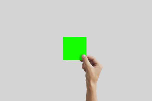 Right hand holding green square paper in the right hand. Leaflet - Φωτογραφία, εικόνα