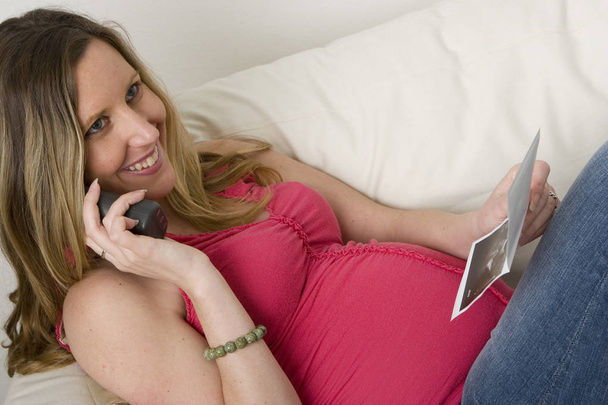 Mulher grávida olhando para uma foto de ultra-som de seu bebê
 - Foto, Imagem