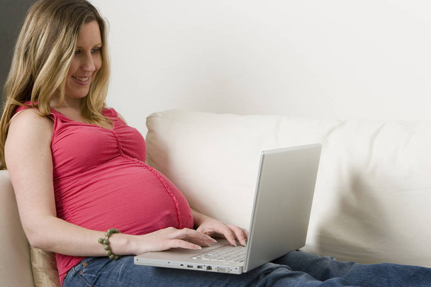 Pregnant woman typing on the computer. - Foto, afbeelding