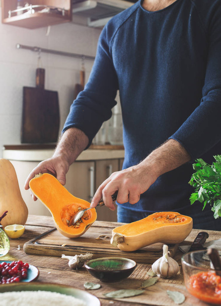 Man preparing healthy food of squash on wooden table - Photo, image
