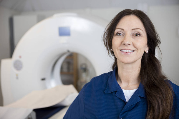 Smiling Female Professional Against MRI Machine In Hospital - Photo, Image