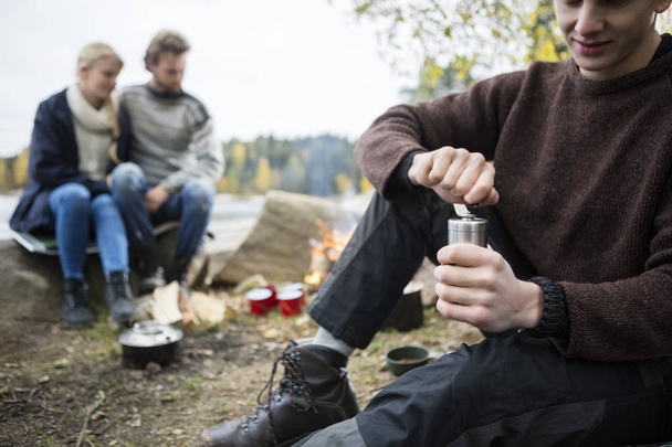 Man Grinding Coffee With Friends At Campsite - Foto, Imagem