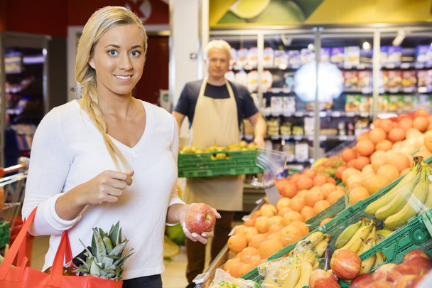 Smiling Customer Holding Apple In Supermarket - Zdjęcie, obraz