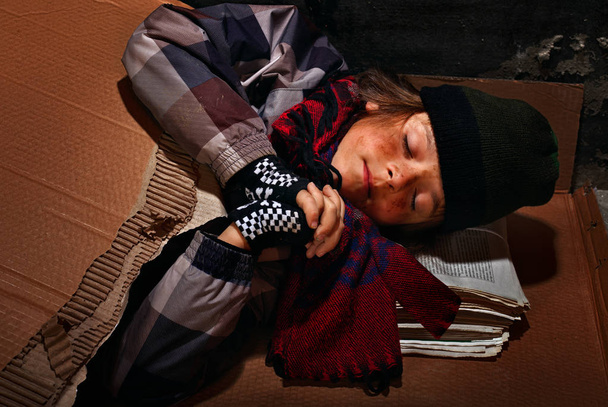Poor beggar boy preparing to sleep on the street - covered with  - Valokuva, kuva