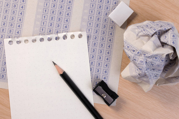 Τσαλακωμένο χαρτί μπάλα από vintage κλασικό απάντηση φύλλο με μολύβι, ξύστρα και χαρτί μείωση. Σταυρός η σωστή απάντηση στο πλαίσιο με κενό απάντηση. Απάντηση φύλλο έννοια. - Φωτογραφία, εικόνα