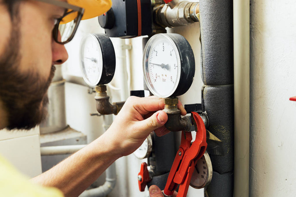 водопровідник встановлює вимірювач тиску для системи опалення будинку
 - Фото, зображення