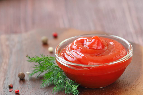 Tomatenketchup saus met kruiden in een glazen kom - Foto, afbeelding