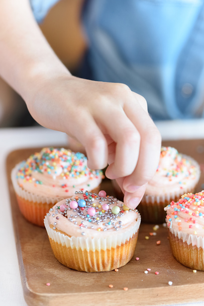 girl putting confetti on cupcakes - Valokuva, kuva