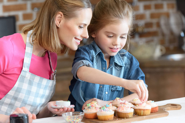 mother and daughter baking cupcakes - 写真・画像