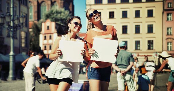 Two smiling girls holding empty board - Fotoğraf, Görsel