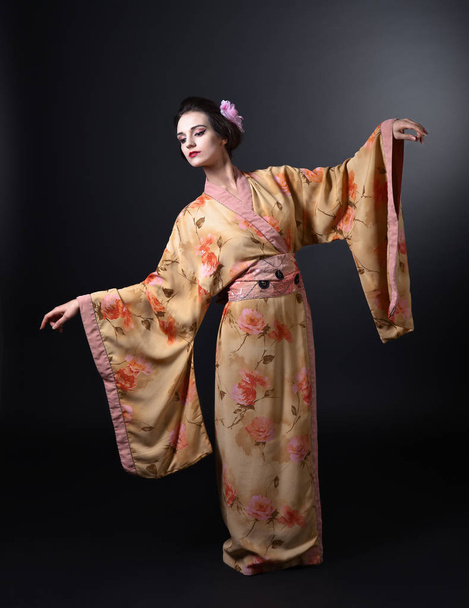 Dansende vrouw in traditionele Japanse kimono op zwarte achtergrond - Foto, afbeelding