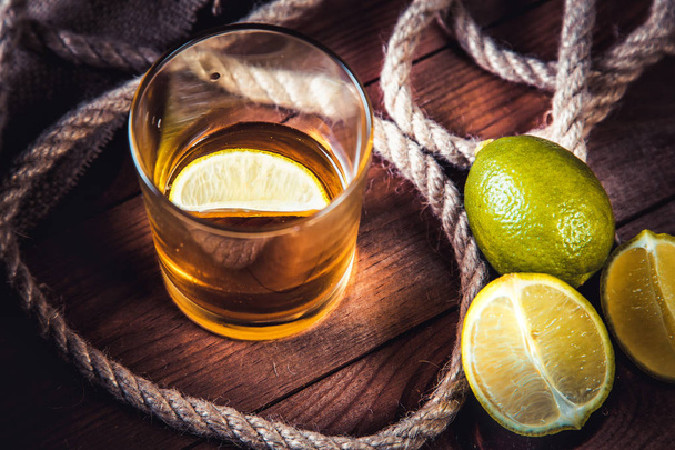 A bottle of whiskey, rum, brandy, lime on a wooden background - Foto, afbeelding