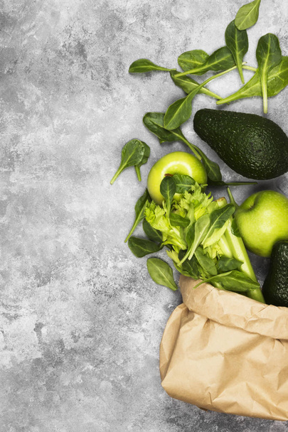 Различные зеленые овощи и фрукты - сельдерей, яблоки, авокадо, шпинат в бумажной упаковке на светлом фоне. Вид сверху, место для копирования. Пищевая спинка
 - Фото, изображение