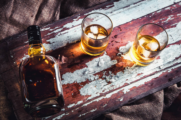 whiskey bottle and glass on a wooden vintage background - Фото, изображение