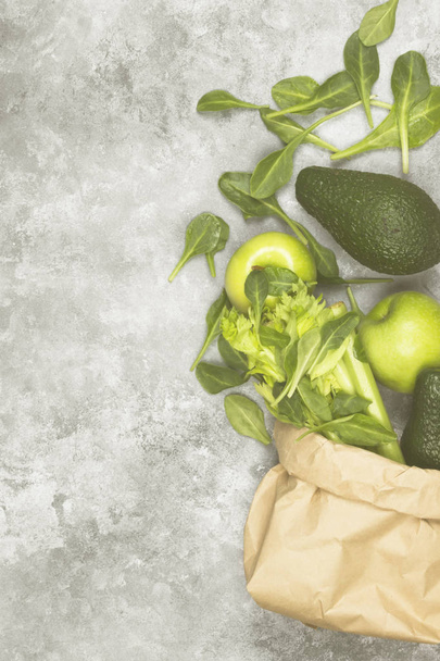 Various green vegetables and fruit - celery, apples, avocado, spinach in a paper package on a light background. Top view, copy space. Food background. Toning - Φωτογραφία, εικόνα