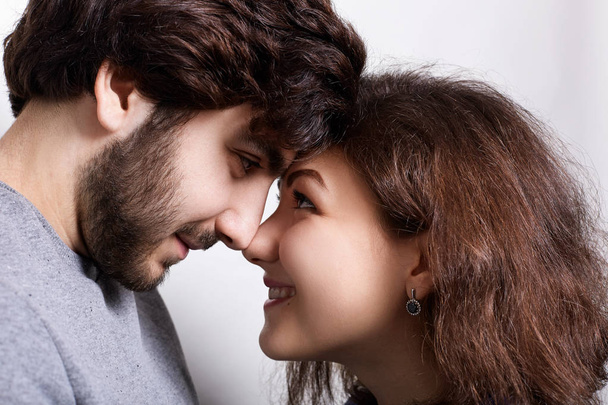 Happy couple in love touching noses smiling and looking at each other`s words. Close-up nose to nose. Couple in love touching noses. Young couple standing close face to face and touching by noses. - Foto, imagen