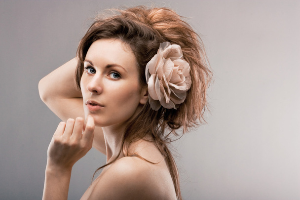 Young beautiful girl with a rose in hair - Фото, зображення