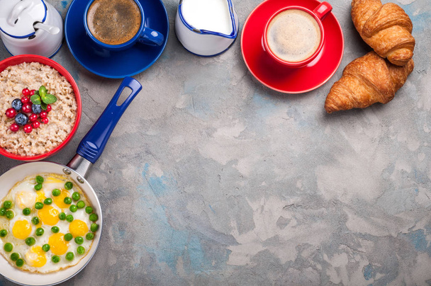 Традиционный завтрак с яйцами, овсяной кашей, круассанами и кофе на сером фоне с копировальным пространством
 - Фото, изображение