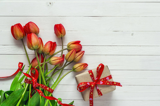 Red tulips and gift box with red ribbon on a white painted woode - Φωτογραφία, εικόνα