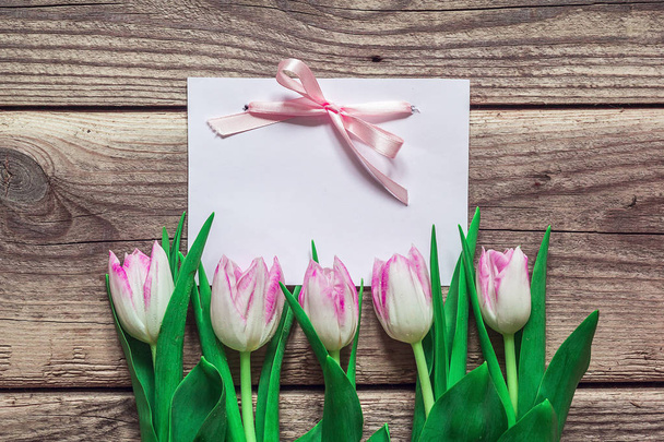 Background with blank card and pink tulips on grunge wooden boar - Фото, изображение
