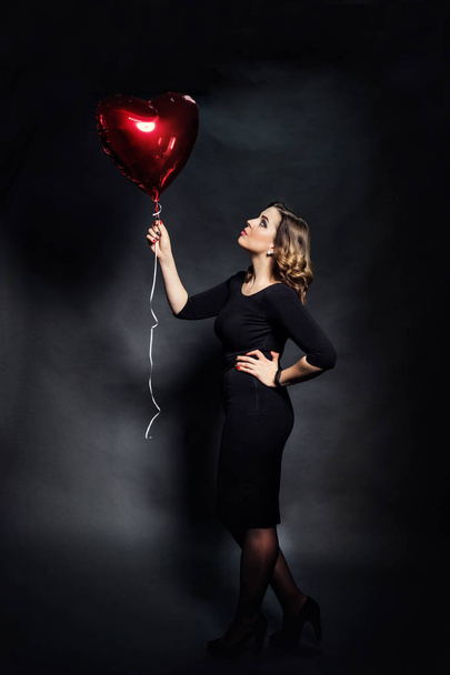 Beautiful girl holding a big red balloon in the form of hearts,Valentine's Day.Red hearts close up,Beauty portrait of female face with  make up, sexy gloss lips make-up and dark eyebrows,makeup concept - Φωτογραφία, εικόνα