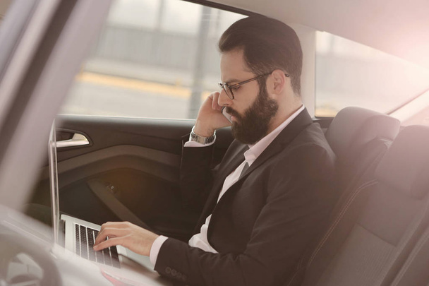 Businessman using lapptop in car - Photo, image