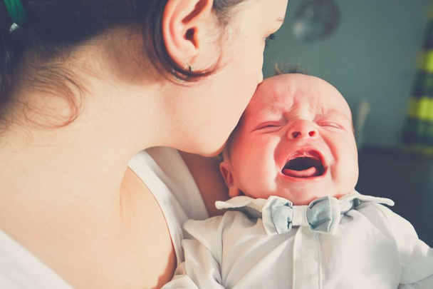 Mother holding crying baby - Фото, изображение