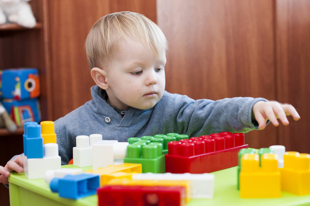 niño pequeño que busca un constuctor de juguete en interiores
 - Foto, Imagen