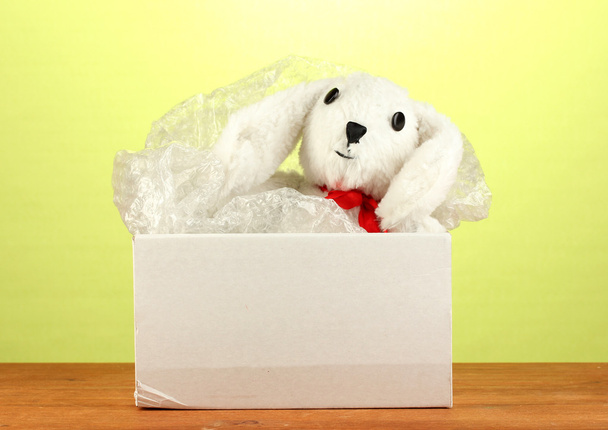 Opened parcel with a child's toy on green background close-up - 写真・画像
