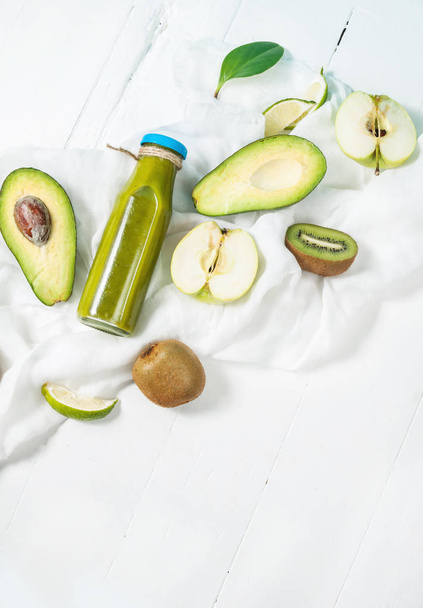 grüner Smoothie in Flaschen mit Avocado, Apfel und Kiwi auf weißem Holzhintergrund - Foto, Bild