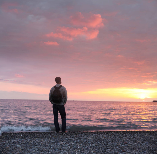 yksin mies katselee auringonlaskua rannalla
 - Valokuva, kuva
